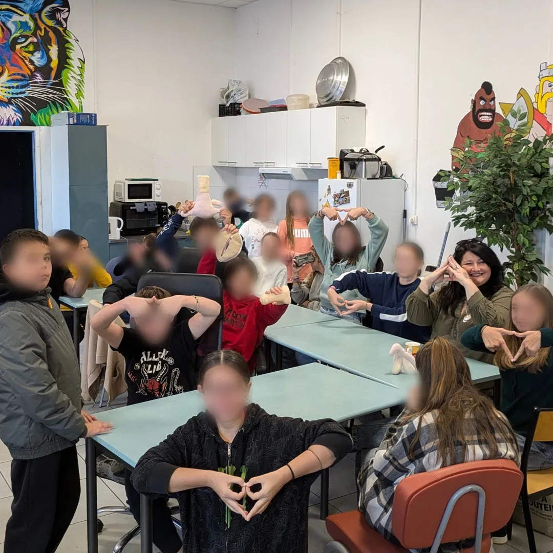 Un groupe d’adolescents et leur animatrice formant des cœurs avec les mains, en fin d’atelier